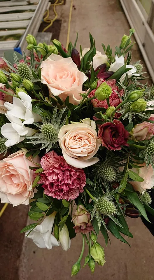 Närbild på brudbukett med rosa rosor och tistel